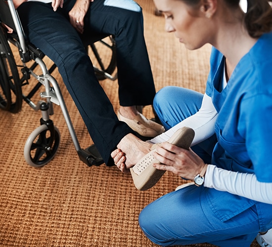 caregiver helping put footwear on a senior patient